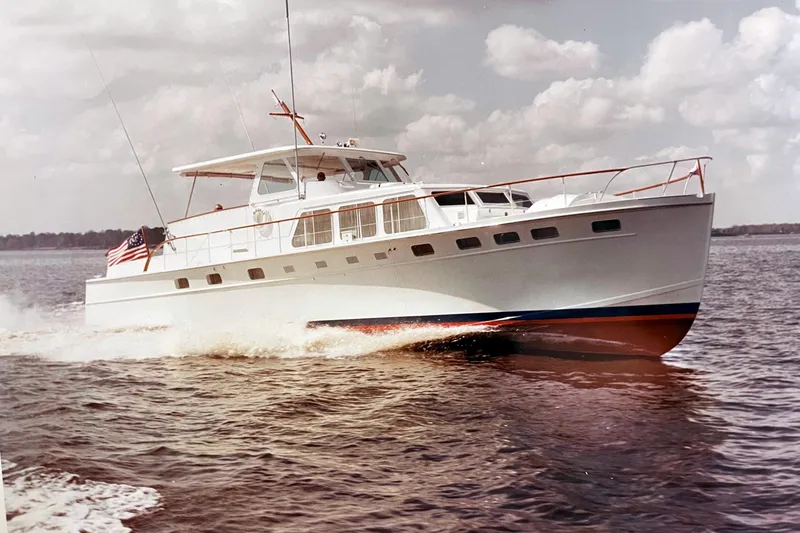 Slide: The Image of 1967 Huckins Linwood 53 yacht cruising on open water under a cloudy sky. - 1