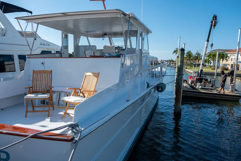 Slide: The Image of 1967 Huckins Linwood 53 yacht docked, featuring wooden chairs on deck under clear blue sky. - 6