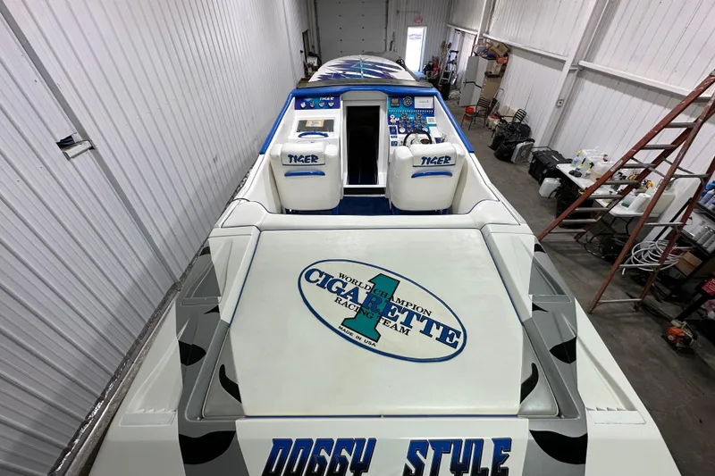 Slide: The Image of 2000 Cigarette 42' Tiger boat in a garage, showcasing sleek design and racing team logo. - 10