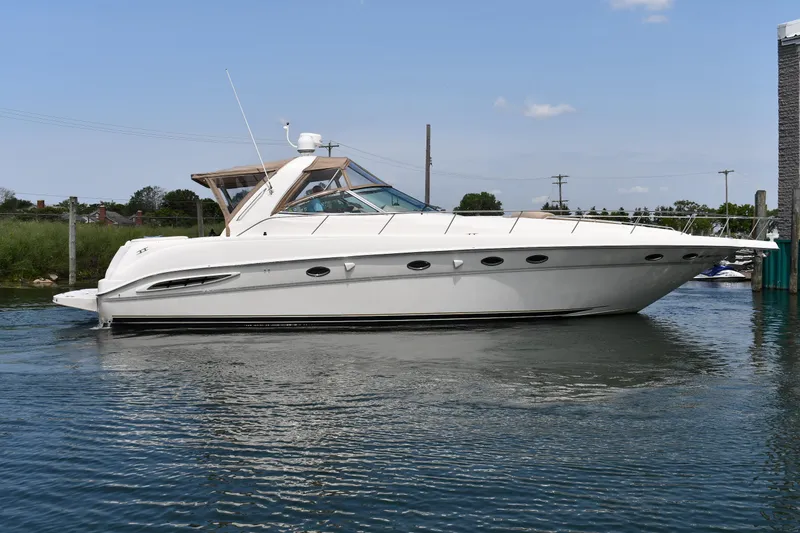 The Image of A white 2000 Sea Ray Sundancer 460 sits calmly on the water, surrounded by nature. - 0