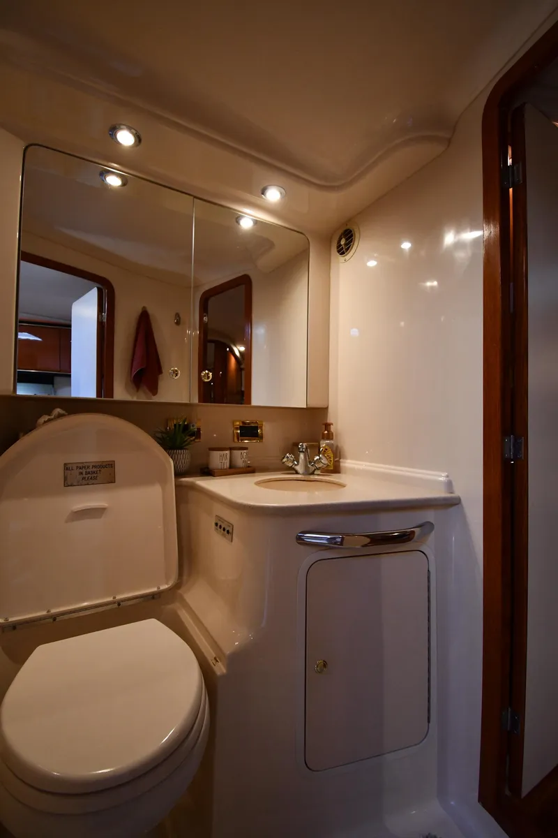Slide: The Image of Interior view of a boat bathroom with toilet, sink, and mirror. Wood trim and lighting present. - 43