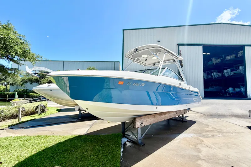 Slide: The Image of 2012 Robalo R247 Dual Console boat in storage, blue hull, sunny day. - 1