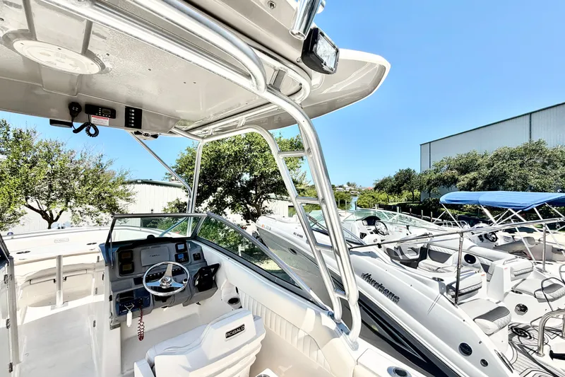 Slide: The Image of 2012 Robalo R247 Dual Console boat interior with steering wheel and seating, docked under clear sky. - 10
