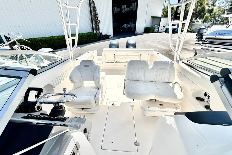 Slide: The Image of 2012 Robalo R247 Dual Console boat interior with white seating and steering wheel. - 17