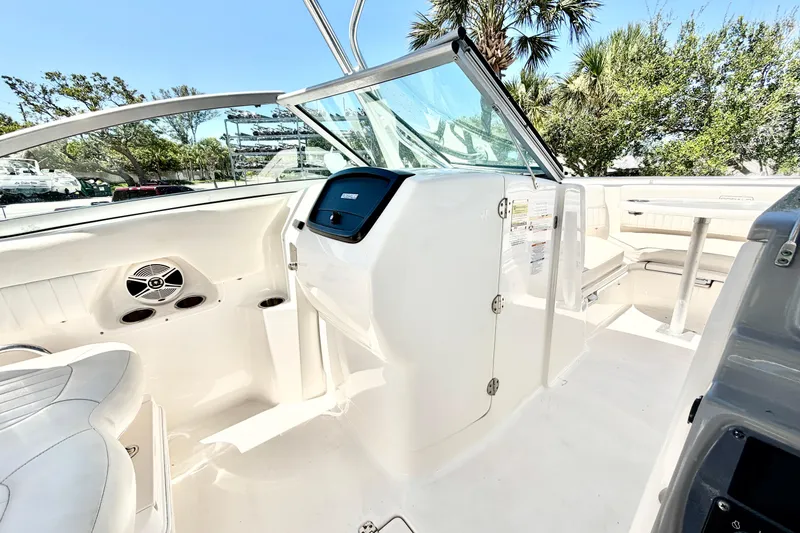 Slide: The Image of 2012 Robalo R247 Dual Console boat interior with seating and console, surrounded by trees. - 20