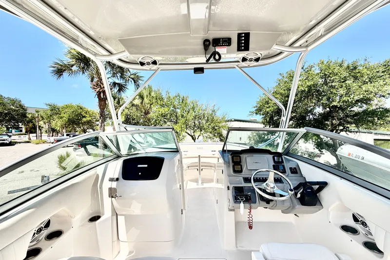 Slide: The Image of 2012 Robalo R247 Dual Console boat interior with steering wheel and dashboard, surrounded by trees. - 22