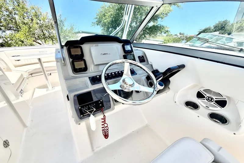 Slide: The Image of 2012 Robalo R247 Dual Console boat cockpit with steering wheel and control panel. - 23