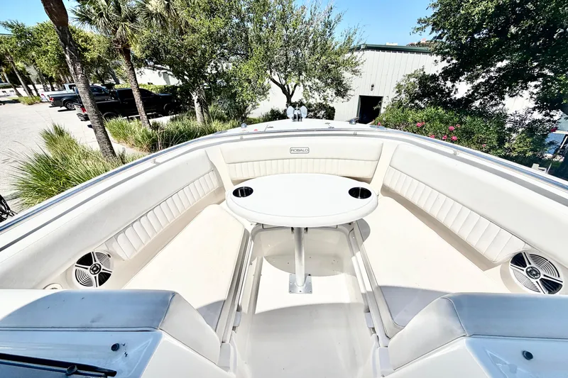 Slide: The Image of 2012 Robalo R247 Dual Console boat interior with seating and table, surrounded by greenery. - 26