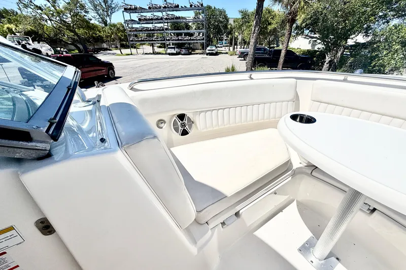 Slide: The Image of 2012 Robalo R247 Dual Console boat interior with seating and table, parked outdoors. - 27
