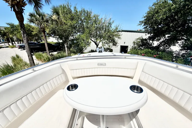 Slide: The Image of 2012 Robalo R247 Dual Console boat interior with seating and table, surrounded by trees. - 28