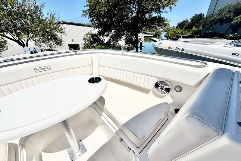 Slide: The Image of 2012 Robalo R247 Dual Console boat interior with seating and table, docked near water. - 29