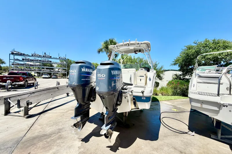 Slide: The Image of 2012 Robalo R247 Dual Console boat with twin Yamaha 150 engines, parked outdoors. - 4