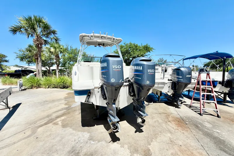 Slide: The Image of 2012 Robalo R247 Dual Console boat with twin Yamaha 150 engines, parked outdoors. - 5