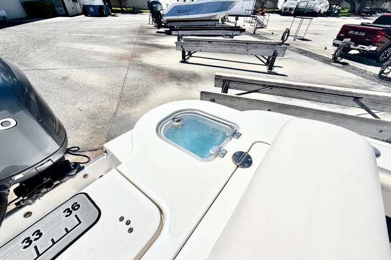 Slide: The Image of 2012 Robalo R247 Dual Console boat with outboard motor and livewell, parked on concrete. - 7