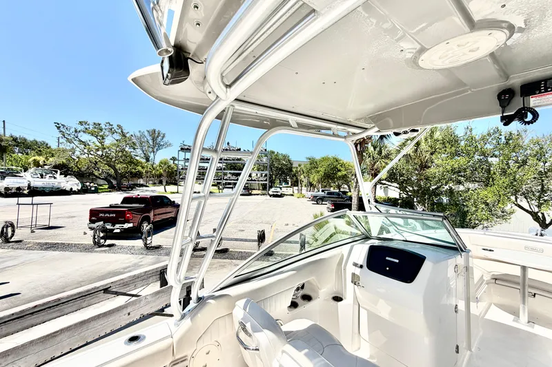 Slide: The Image of 2012 Robalo R247 Dual Console boat interior with T-top, parked near trees and vehicles. - 8