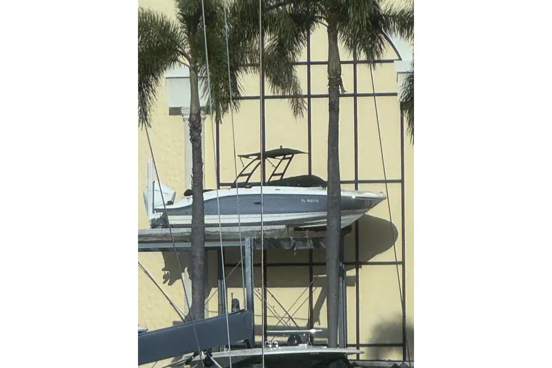 Slide: The Image of 2023 Sea Ray SPX 210 Outboard boat displayed on a lift with palm trees. - 1