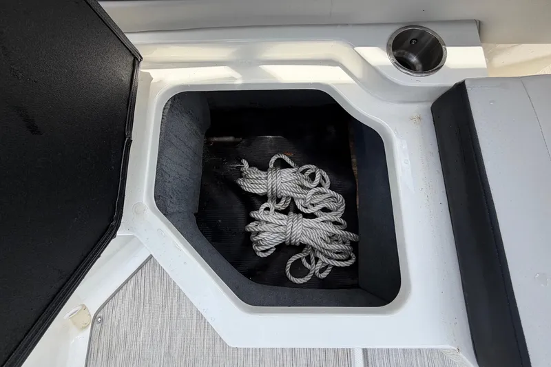 Slide: The Image of An open storage compartment on a Sea Ray SPX 210 Outboard boat with rope inside. - 44