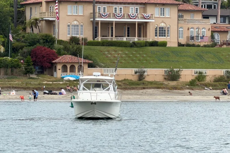 Slide: The Image of 2008 Scout 295 Abaco boat on water near a large waterfront house with lush greenery. - 2