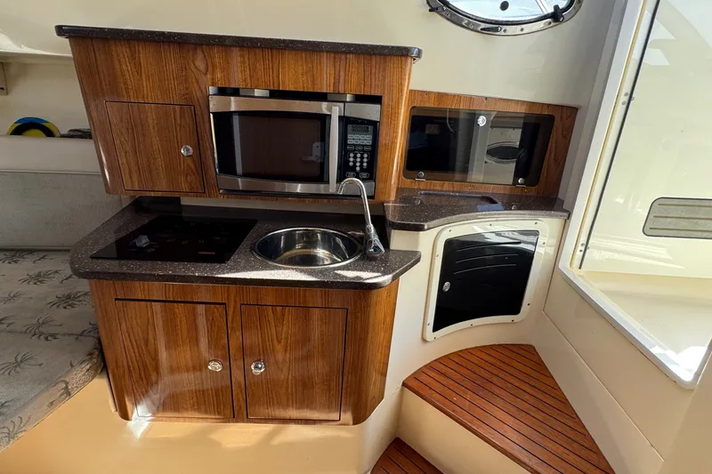 Slide: The Image of 2008 Scout 295 Abaco boat interior with kitchenette, featuring wood cabinets and modern appliances. - 32