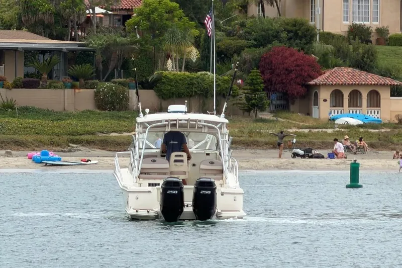 Slide: The Image of 2008 Scout 295 Abaco boat cruising near a scenic shoreline with beachgoers. - 5