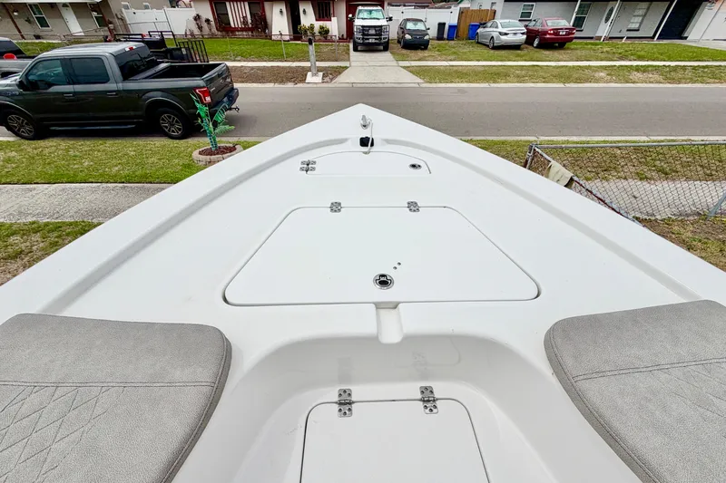 Slide: The Image of 2025 Sea Pro 230 Bay boat deck, featuring storage compartments and seating, parked in a residential area. - 12