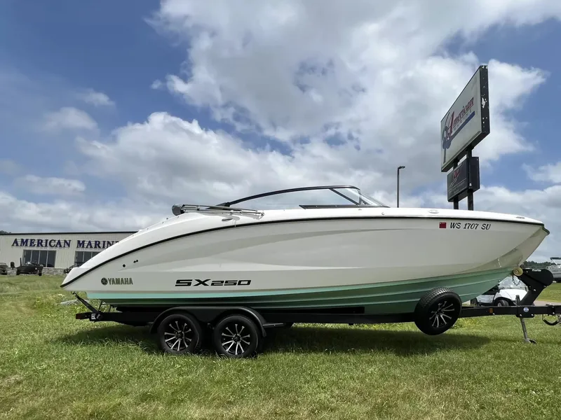 The Image of Yamaha SX250 boat from 2023 on a trailer, parked on grass in front of a store. - 1