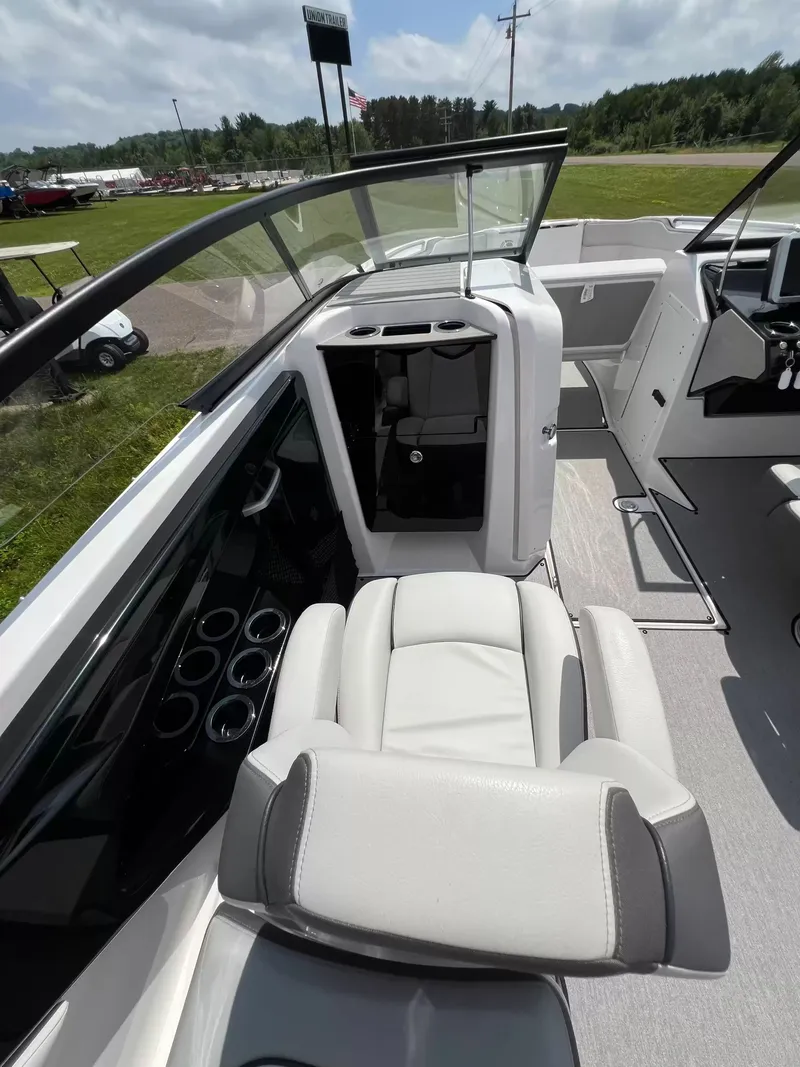 Slide: The Image of Interior of a 2023 Yamaha SX250 with white and gray seating, glass windows, and a helm station. - 16