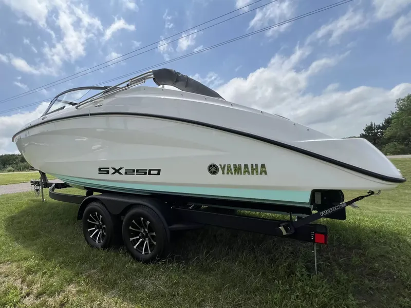 Slide: The Image of A 2023 Yamaha SX250 boat on a trailer, set on grass under a cloudy sky. - 4