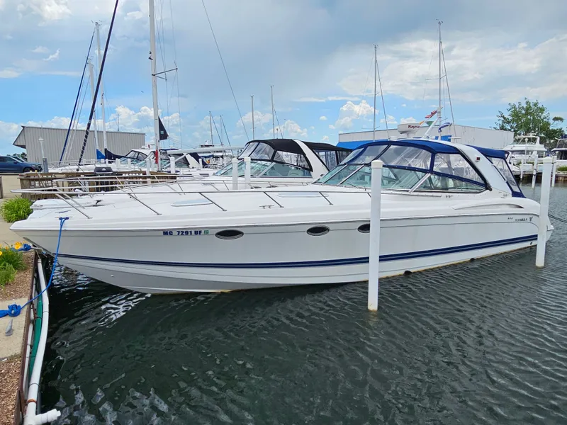 The Image of A white motorboat docked, featuring blue accents and an enclosed cockpit. - 0