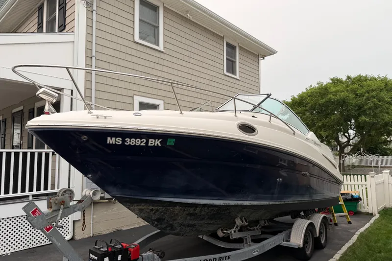 Slide: The Image of 2006 Sea Ray 240 Sundancer boat on trailer, parked beside a house. - 1