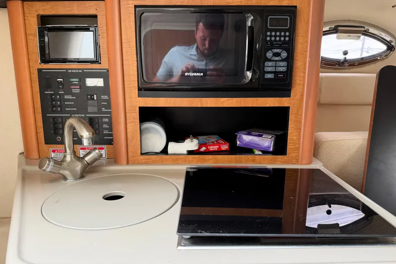 Slide: The Image of 2006 Sea Ray 240 Sundancer interior with kitchenette, microwave, and control panel. - 17