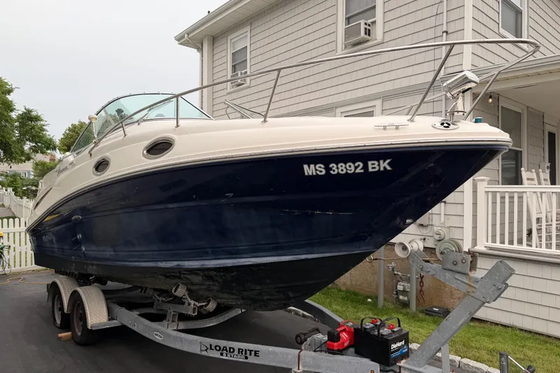 Slide: The Image of 2006 Sea Ray 240 Sundancer boat on trailer, parked beside a house. - 2