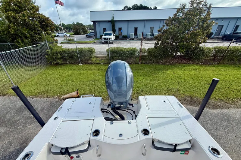 Slide: The Image of 2023 Robalo 206 Cayman boat with outboard motor, parked near a building and flag. - 8