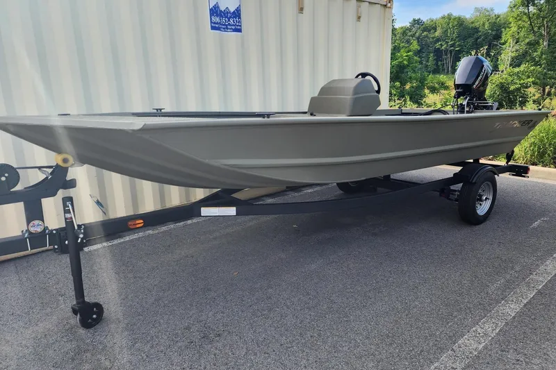 The Image of 2026 Tracker Grizzly 1648 SC boat on trailer, parked outdoors near greenery. - 0