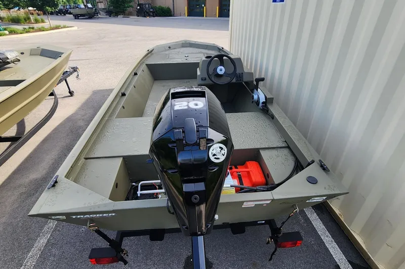 Slide: The Image of 2026 Tracker Grizzly 1648 SC boat with 20 HP motor, parked outdoors. - 2