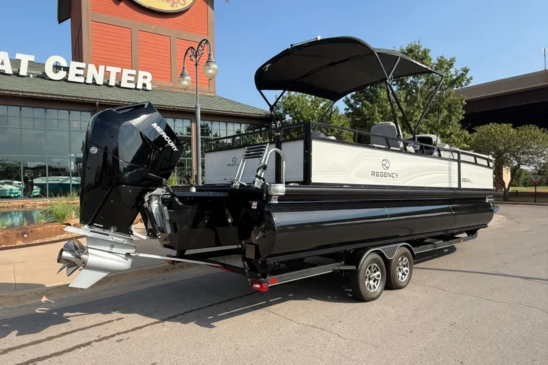 Slide: The Image of 2024 Regency 250 DL3 pontoon boat with Mercury engine, parked outside a boat center. - 12