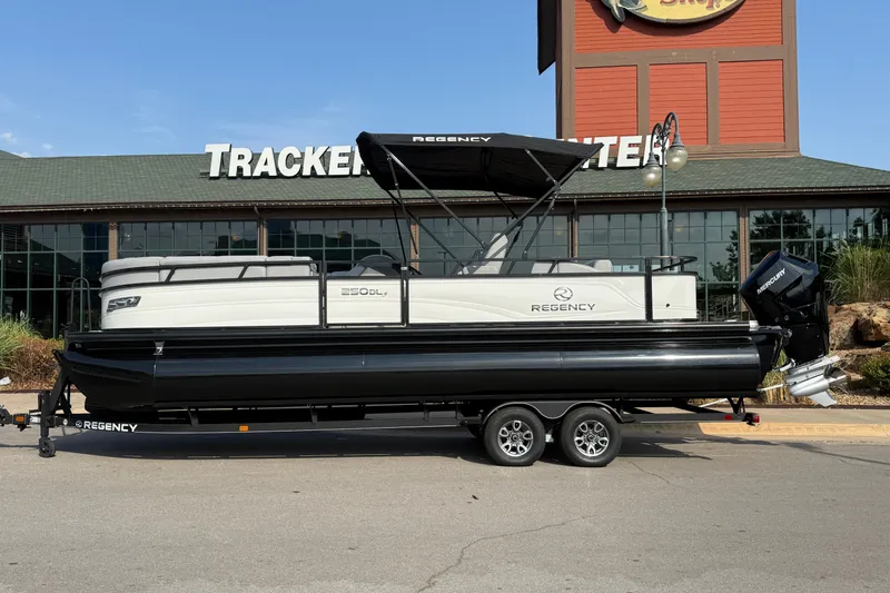 The Image of 2024 Regency 250 DL3 pontoon boat on trailer, parked outside Tracker store. - 0