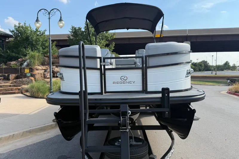 Slide: The Image of 2024 Regency 250 DL3 pontoon boat on trailer, parked outdoors under clear sky. - 3