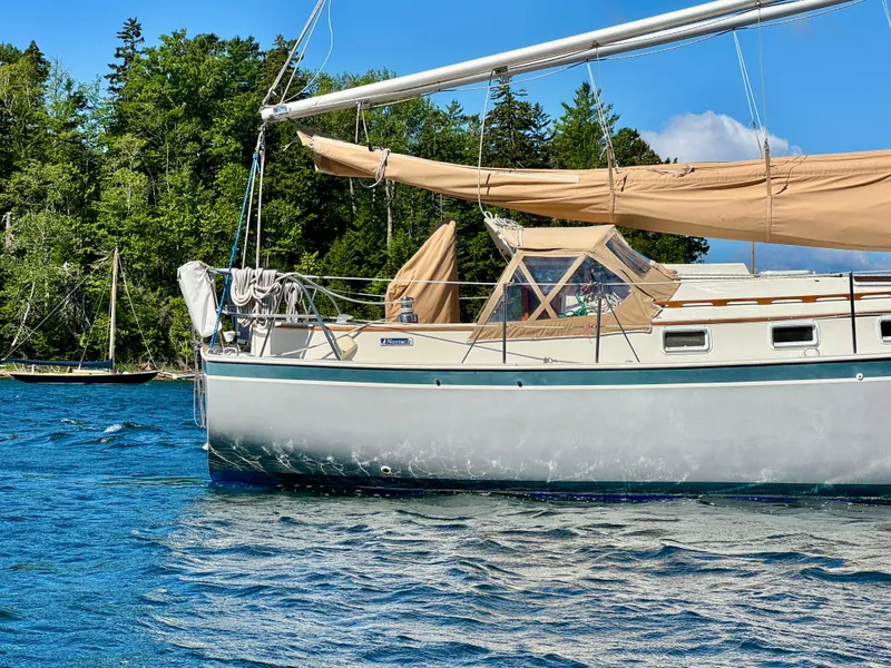 Slide: The Image of 1989 Nonsuch 30 Ultra sailboat on a serene lake with lush green trees. - 12