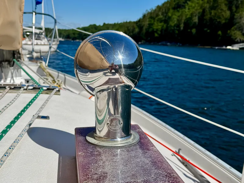 Slide: The Image of Shiny metal fitting on 1989 Nonsuch 30 Ultra sailboat deck, with water and trees in background. - 15