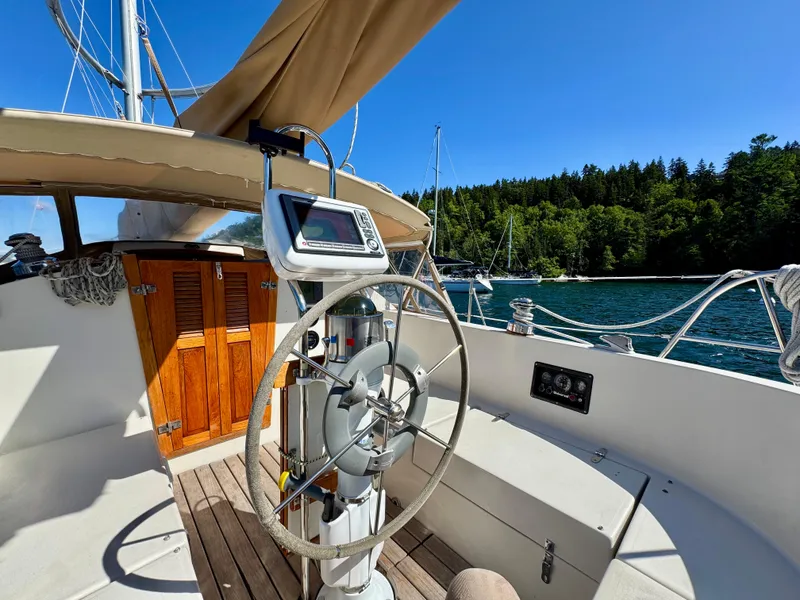 Slide: The Image of 1989 Nonsuch 30 Ultra sailboat cockpit with steering wheel, navigation equipment, and scenic water view. - 27