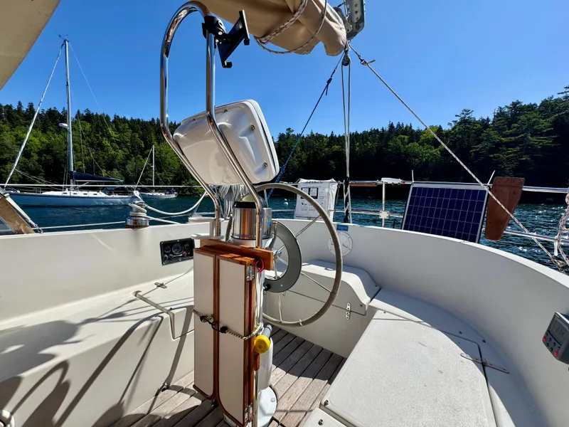 Slide: The Image of 1989 Nonsuch 30 Ultra sailboat cockpit with steering wheel, solar panel, and scenic water view. - 28