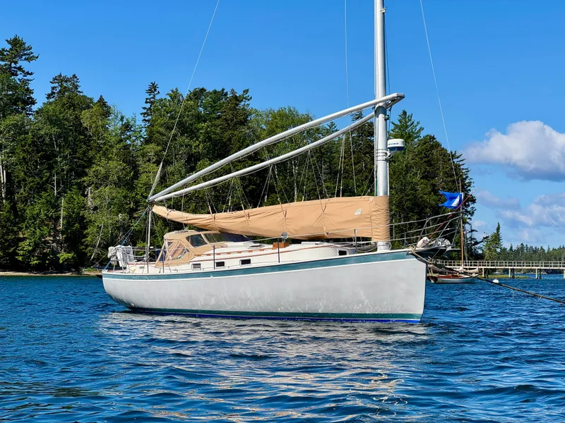 Slide: The Image of Sailboat Nonsuch 30 Ultra 1989 anchored in scenic waters with forested background. - 3