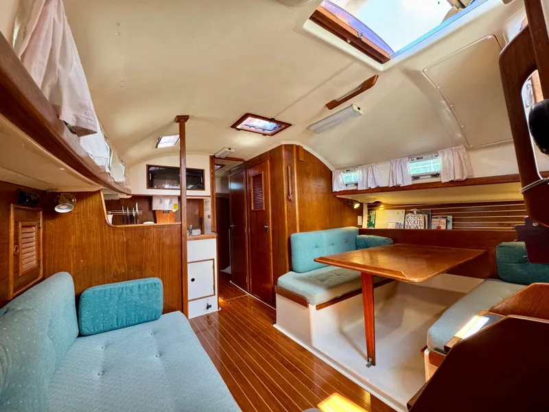 Slide: The Image of 1989 Nonsuch 30 Ultra yacht interior with wood finish and teal seating. - 48