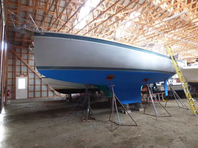 Slide: The Image of 1989 Nonsuch 30 Ultra sailboat in storage, supported by stands, inside a wooden structure. - 7