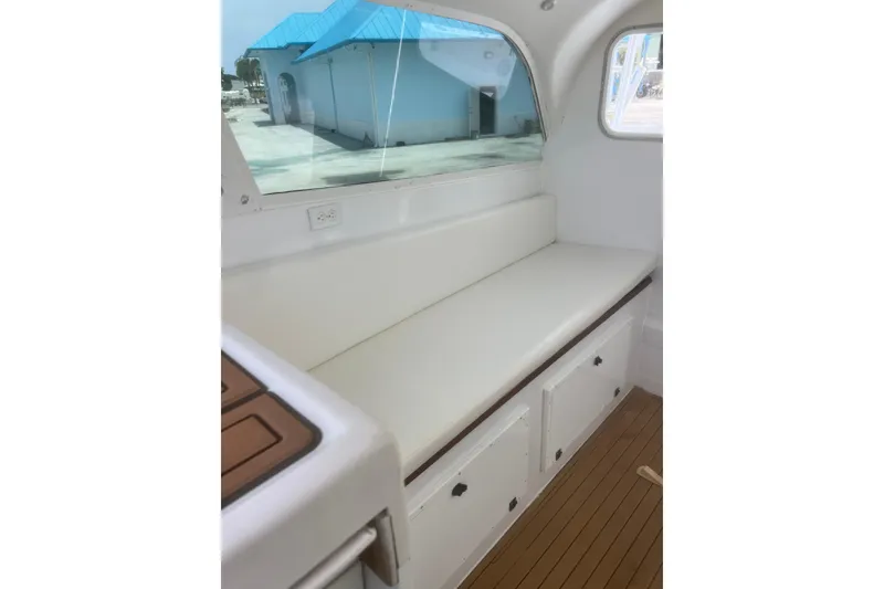 Slide: The Image of Interior of 1973 Bertram 31 Flybridge Cruiser with white seating and wooden flooring. - 28