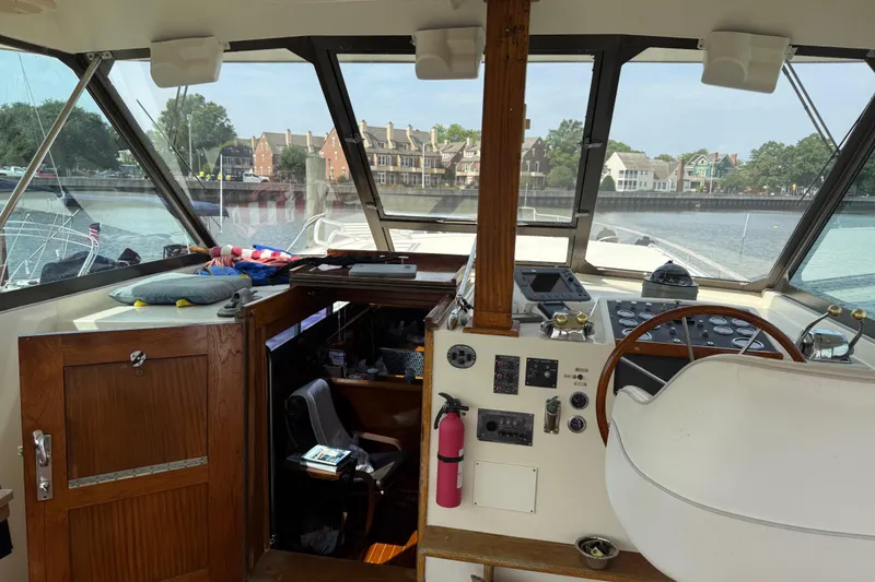 Slide: The Image of Interior view of 1981 Hatteras 43 Motor Yacht helm with wooden accents and waterfront backdrop. - 21