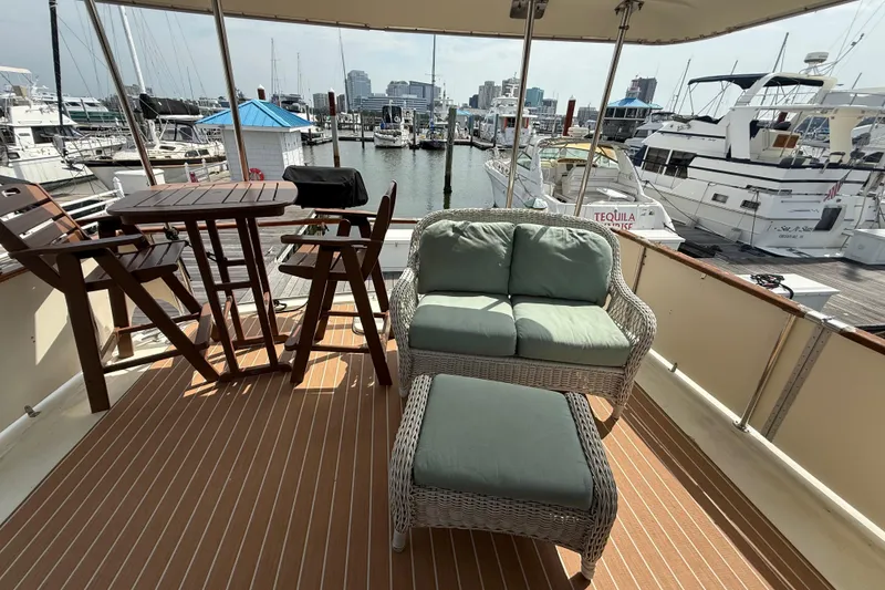 Slide: The Image of 1981 Hatteras 43 Motor Yacht deck with seating, table, and marina view. - 33