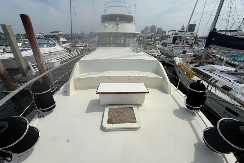 Slide: The Image of 1981 Hatteras 43 Motor Yacht docked at marina, showcasing spacious deck and seating area. - 7