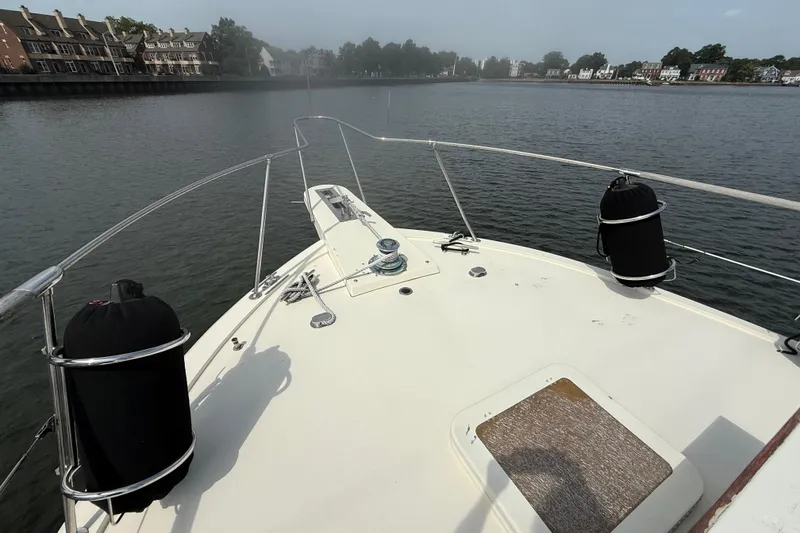 Slide: The Image of Bow view of 1981 Hatteras 43 Motor Yacht on calm water near residential area. - 8